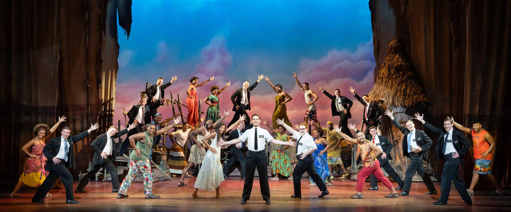 The Book of Mormon cast on stage staring out at the camera.
