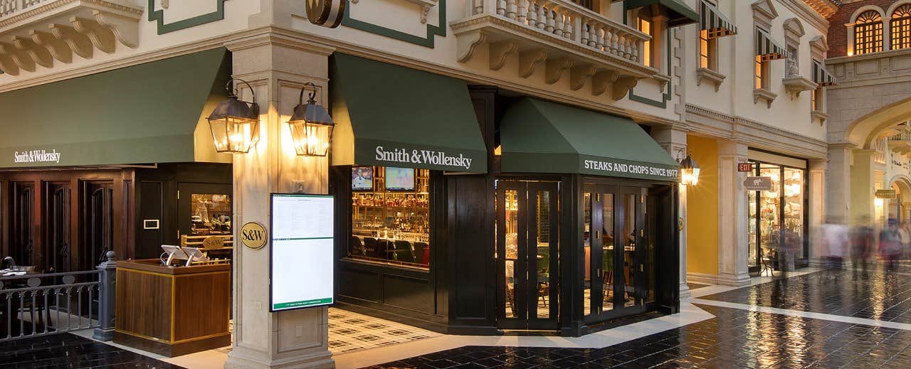 Steakhouse with green awnings on the corner of an indoor shopping center, with a menu display and traditional-style lighting.