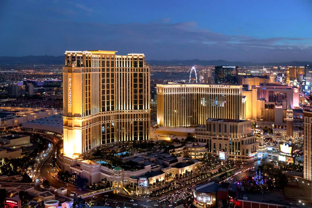 Aerial nighttime view of The Venetian Resort and Palazzo towers illuminated on the Las Vegas Strip.