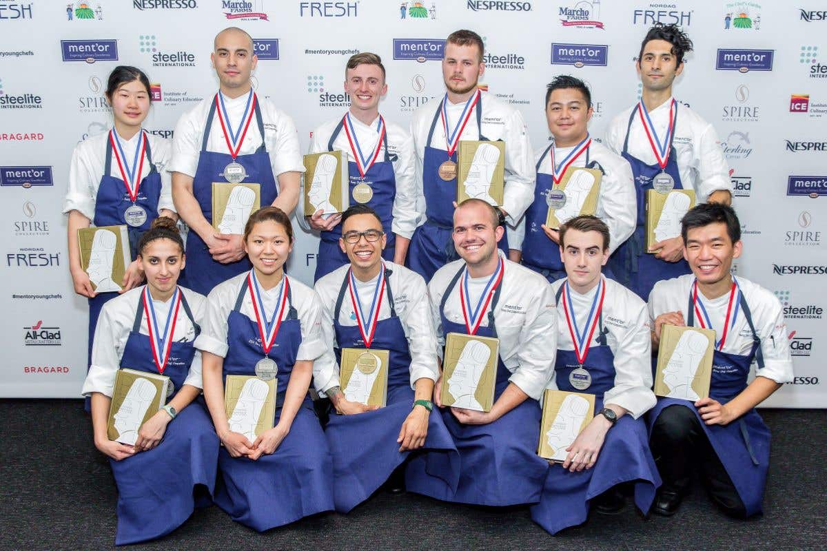 Group of chefs posing with medals and award plaques.