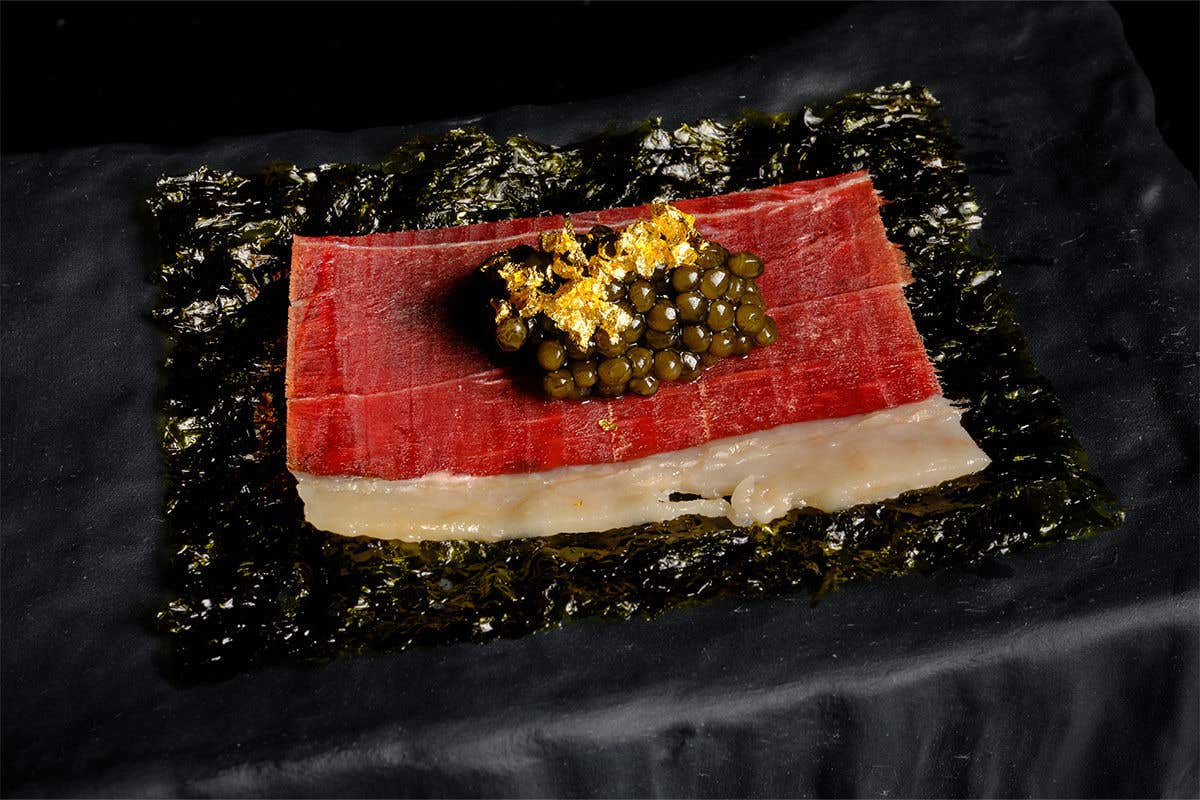 A sheet of toasted nori, topped with jamón ibérico de bellota, a fried quail egg, caviar, and gold leaf