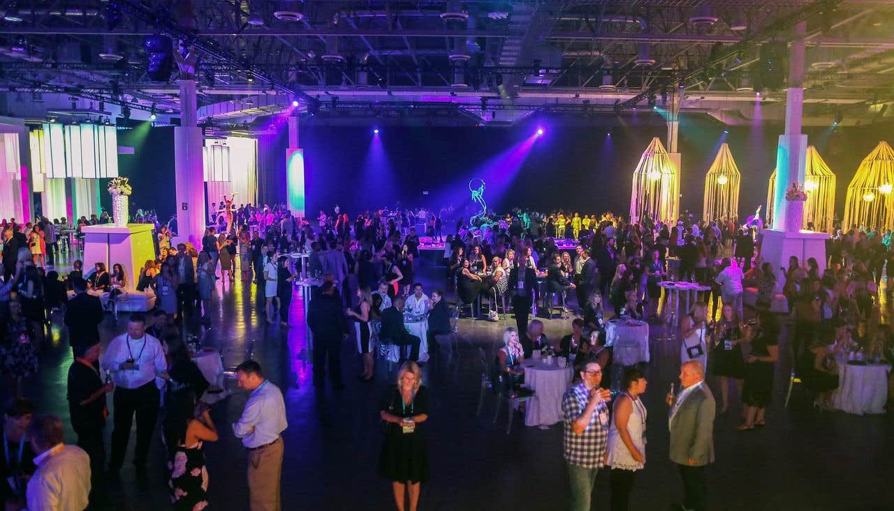 Interior of expo hall c during an event, with  purple lights and people mingling.