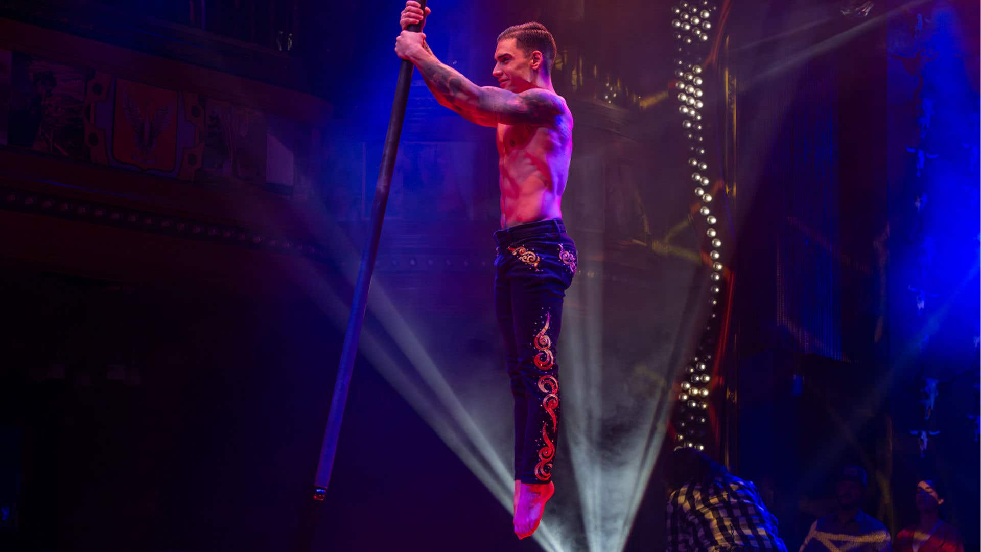 Talent jumping into the air holding a pole and smiling.