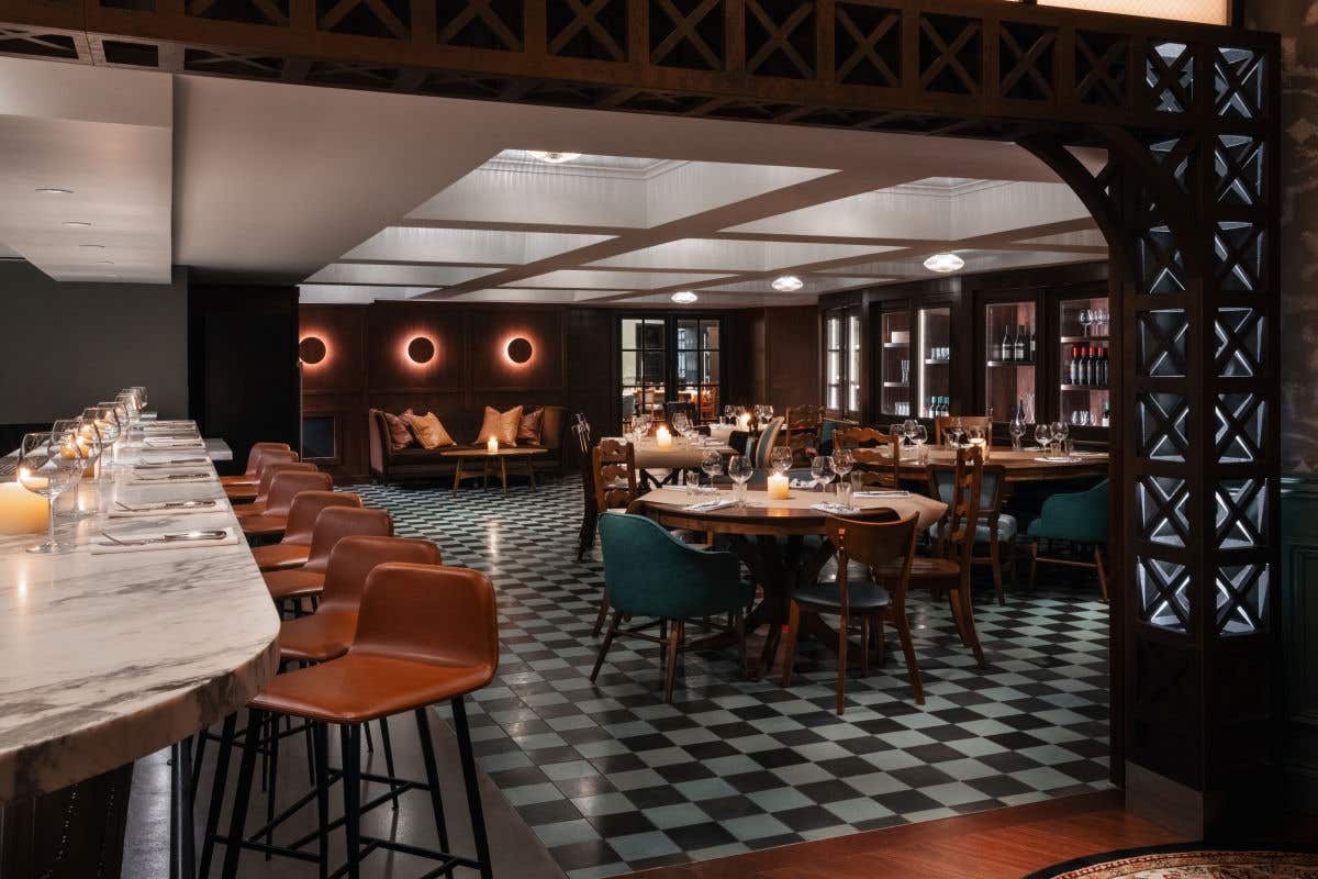 Elegant private dining room with checkered floors, marble bar seating, and warm ambient lighting.
