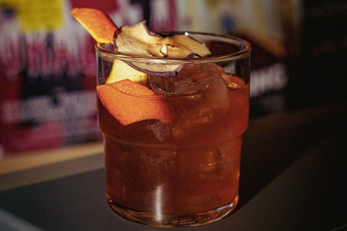 Pale orange cocktail garnished with an orange twist