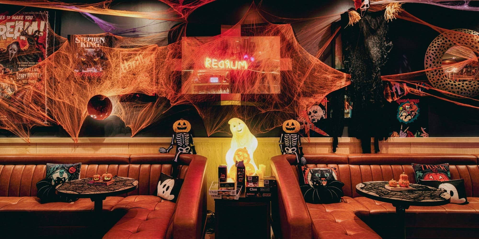 Halloween-themed lounge decorated with spider webs, skeletons, pumpkins, and spooky décor.