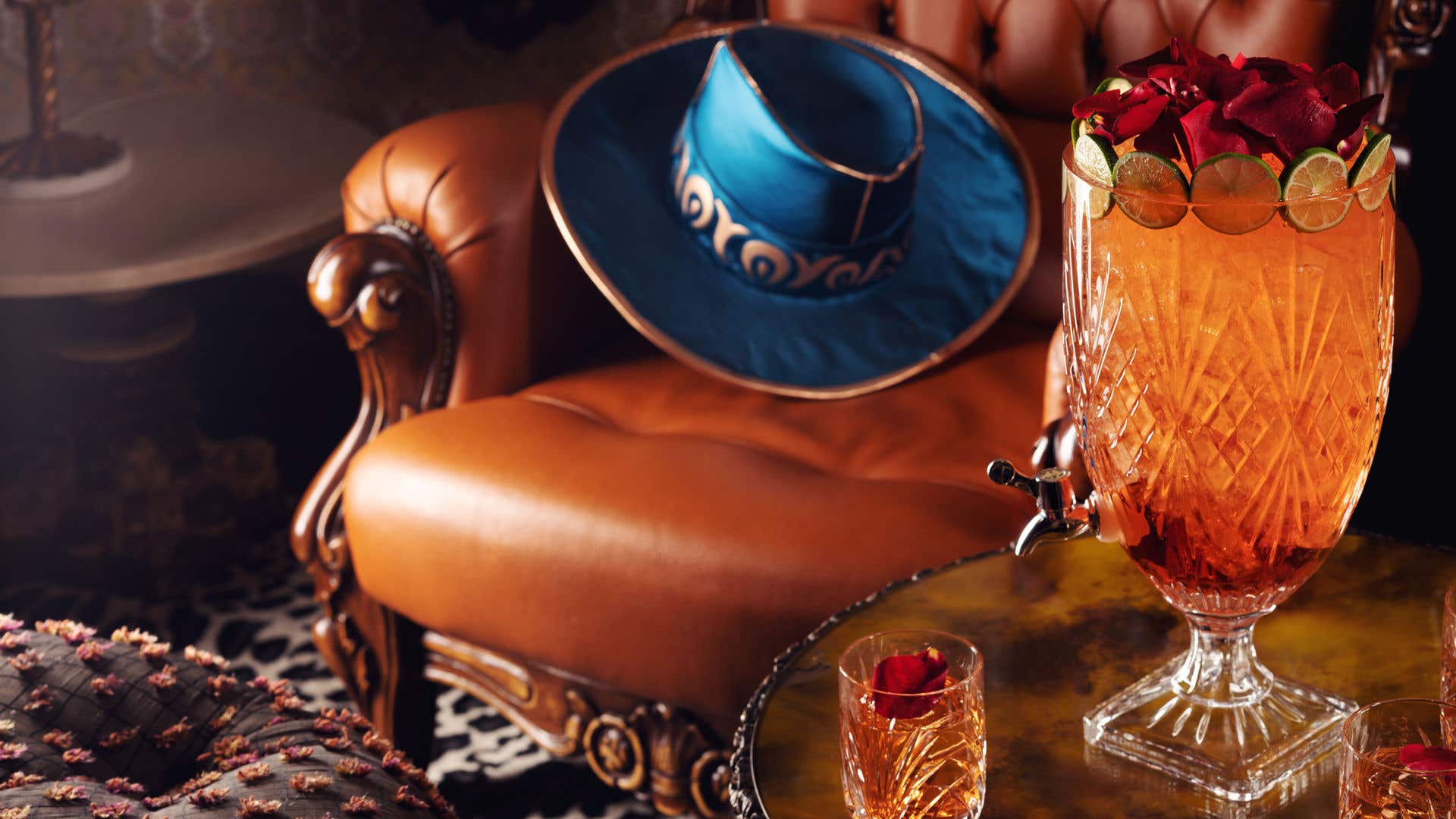 A brown armchair with a blue cowboy hat on it and a side table with drinks on it. 