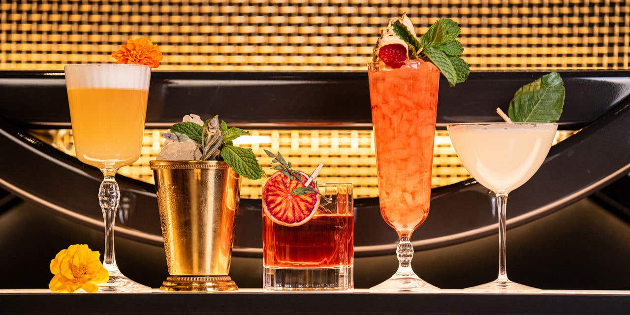 5 assorted cocktails lined up on bar top. 