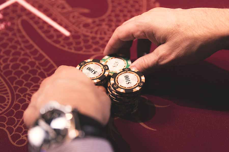 A pair of hands pushing stacks of chips into the centre of a poker table