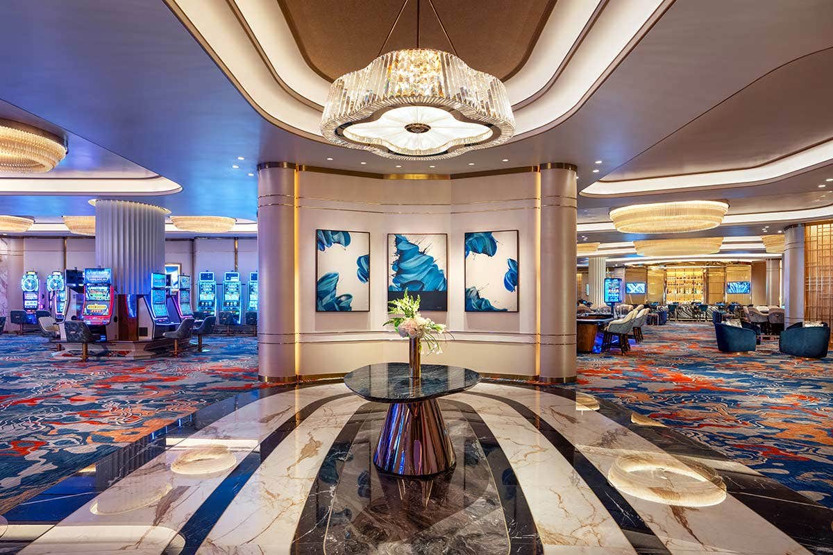 Lobby of casino with a beautiful chandelier, marble floors, slot machines and a lounge area