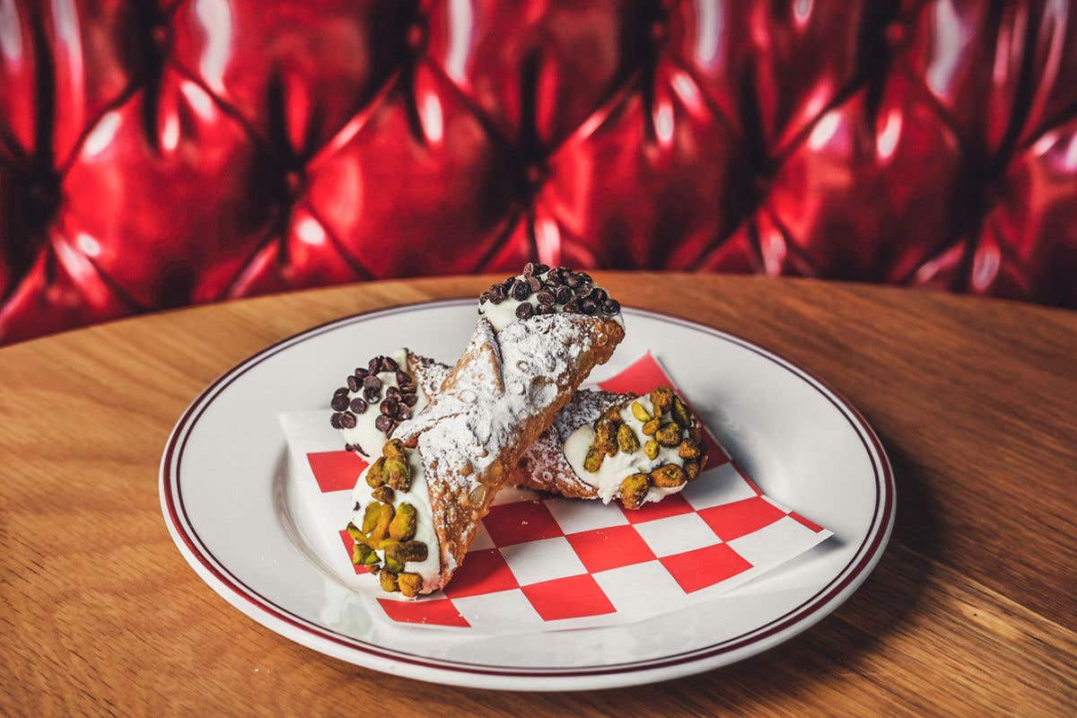 Cannoli filled with cream and topped with pistachios and chocolate chips.