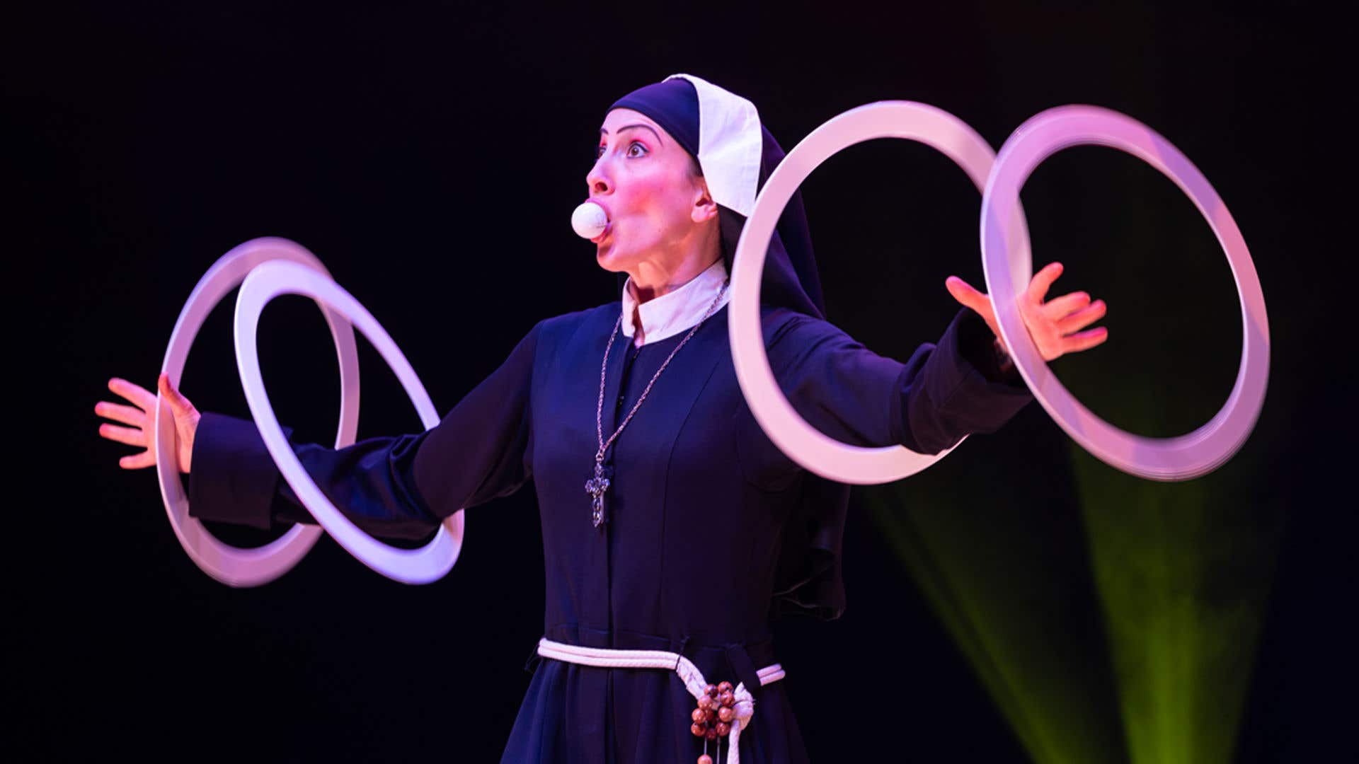 Talent dressed as a nun with a golf ball in her mouth and spinning hoops with her arms.