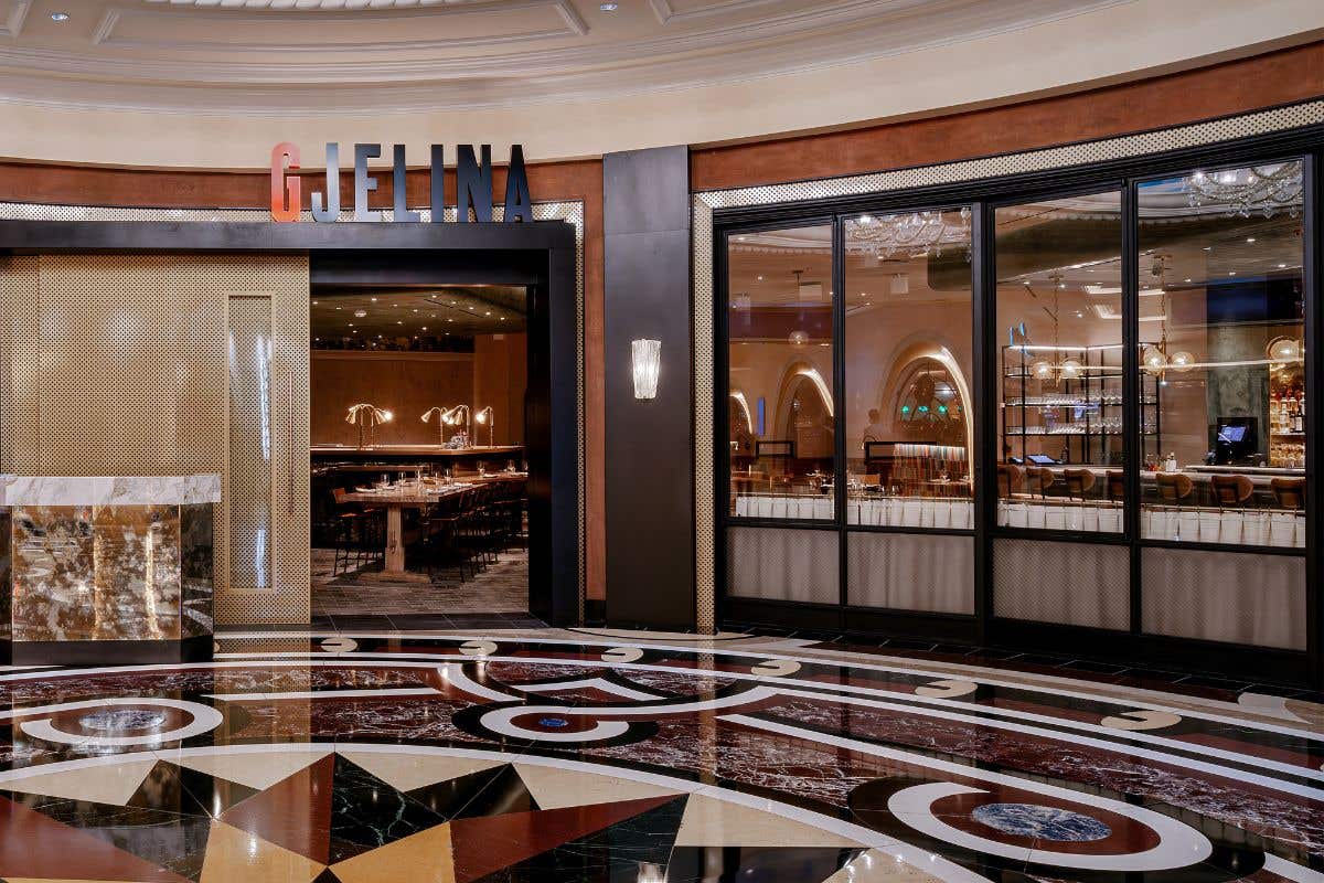 Entrance of Gjelina restaurant with modern design, marble flooring, and a view of the dining area through glass panels.