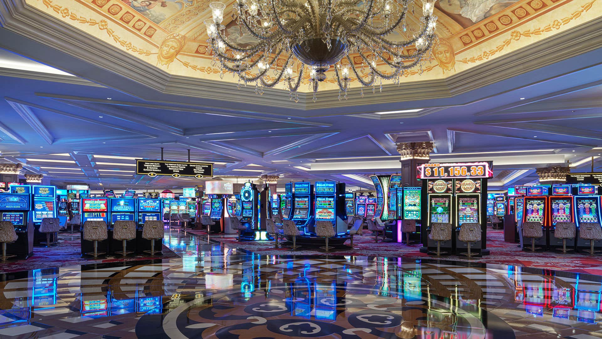 Interior view of the Venetian Casino floor featuring lit slot machines and a chandelier hanging