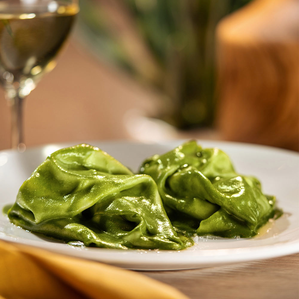Flat sheet pasta in pesto green sauce. 
