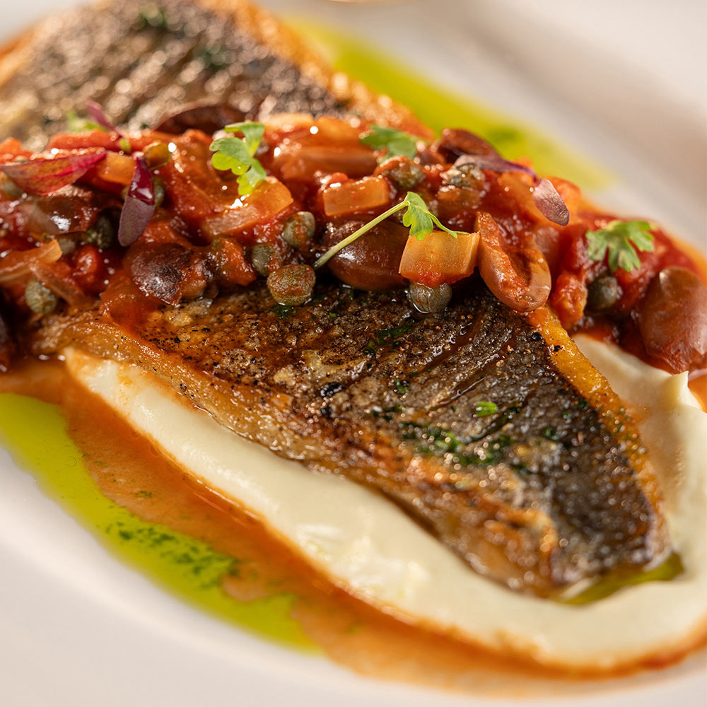 Cooked fish in a sauce and topped with tomato salsa. 