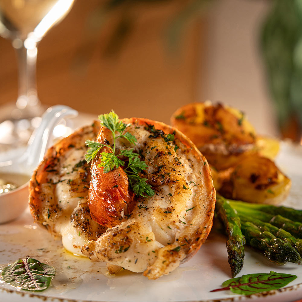Cooked lobster with a side of asparagus and a glass of wine.
